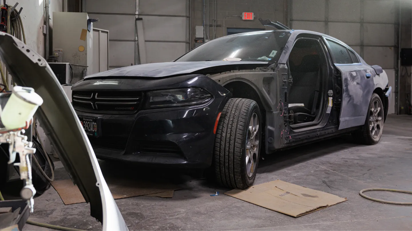 Black Dodge Charger mid-repair on the Best Auto Body shop floor