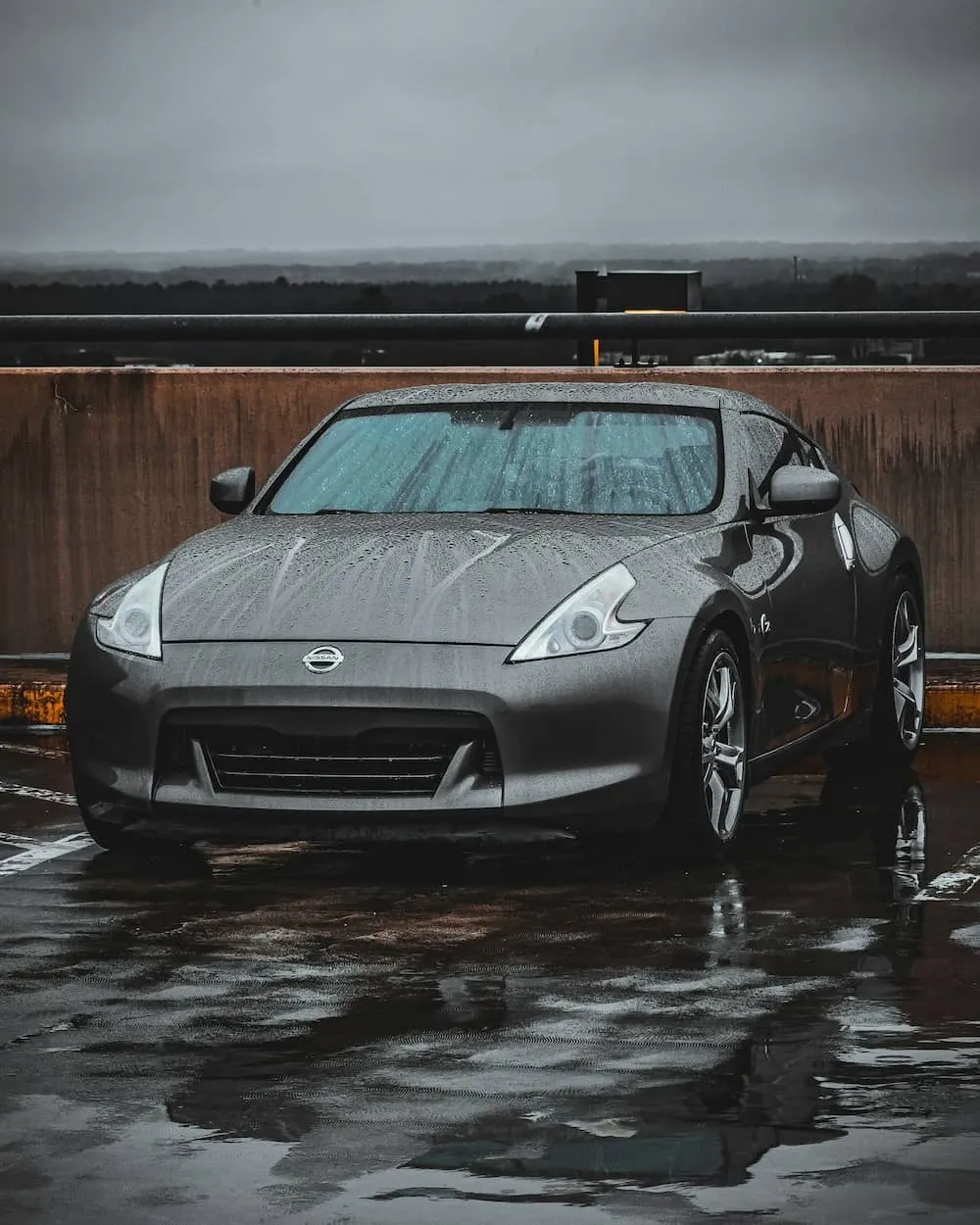 A Nissan car parked in the rain with raindrops on the windows.
